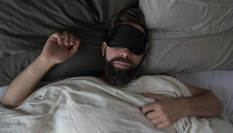high-angle-view-of-man-wearing-sleep-mask-while-royalty-free-image-1682539026.jpg