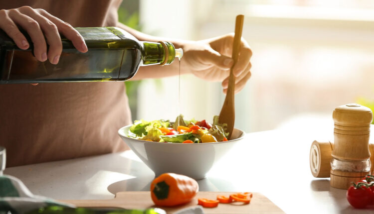 Woman-pouring-olive-oil-into-a-bowl-of-salad.jpg